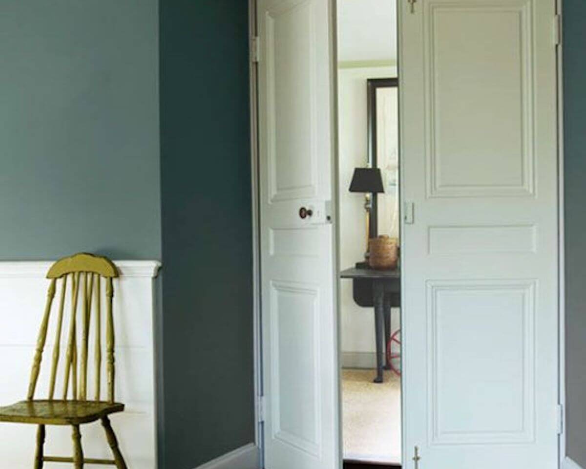 Light green accent chair along dark green wall